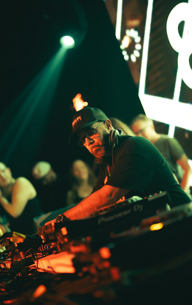 Close-up portrait of a DJ mixing with green and orange stage light