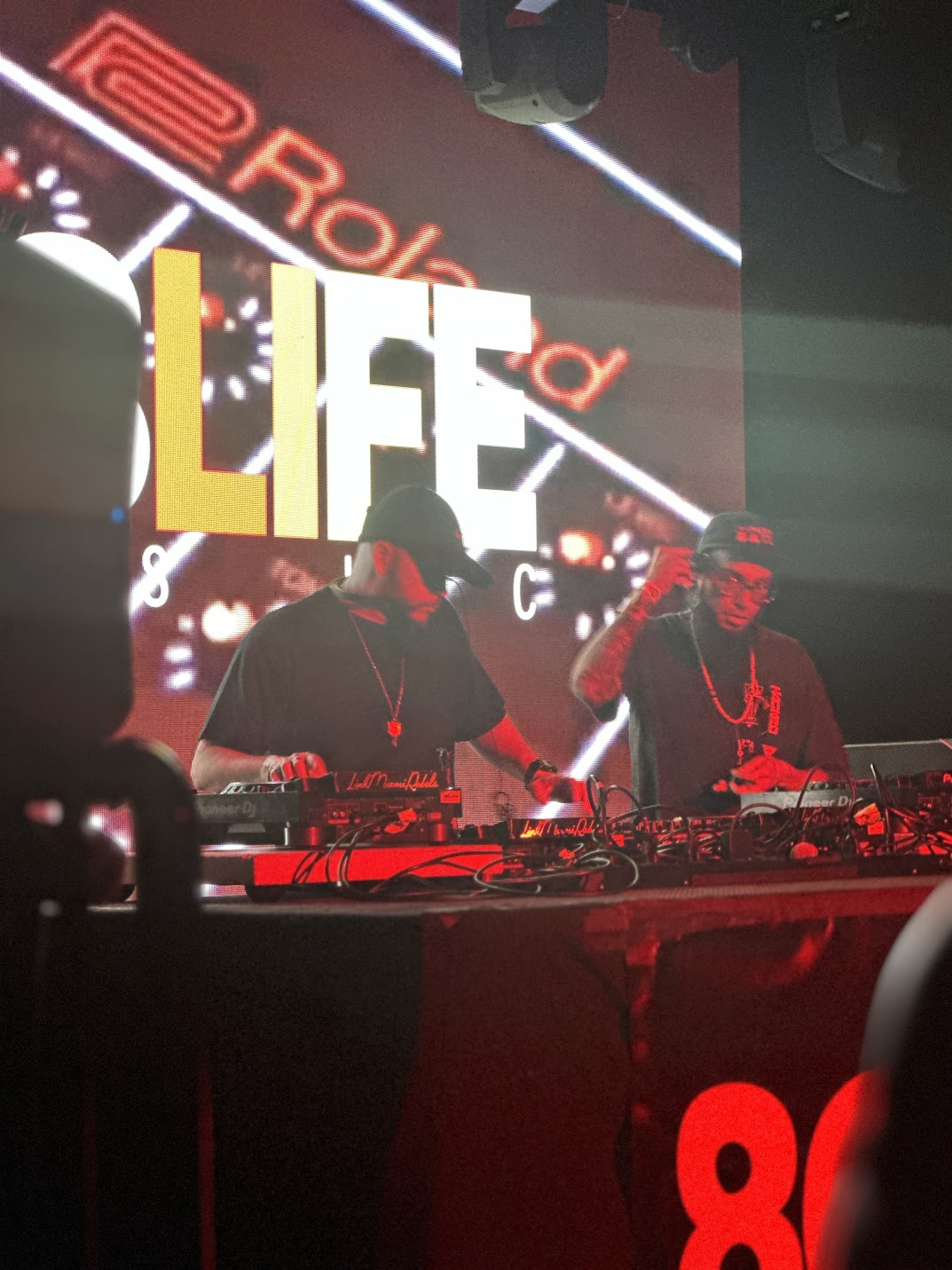 Two DJs performing together under the 808 Life screen